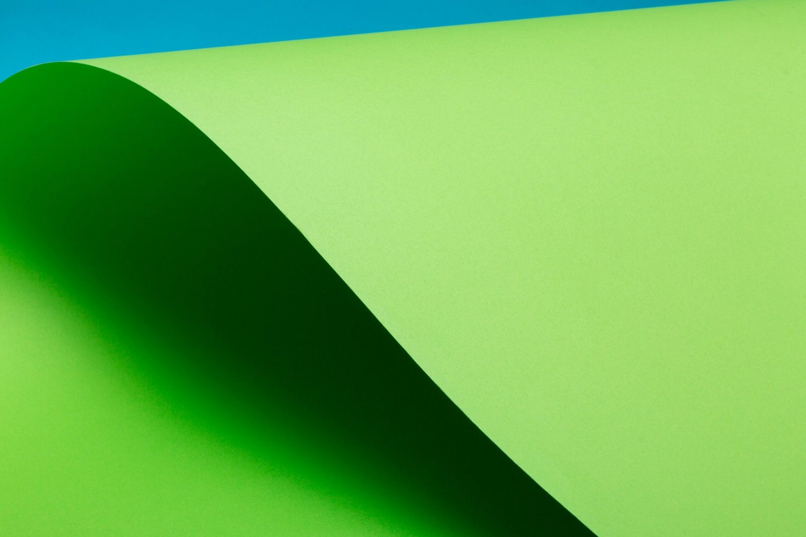A minimalist abstract image with a green curve and blue background, perfect for creative design projects.